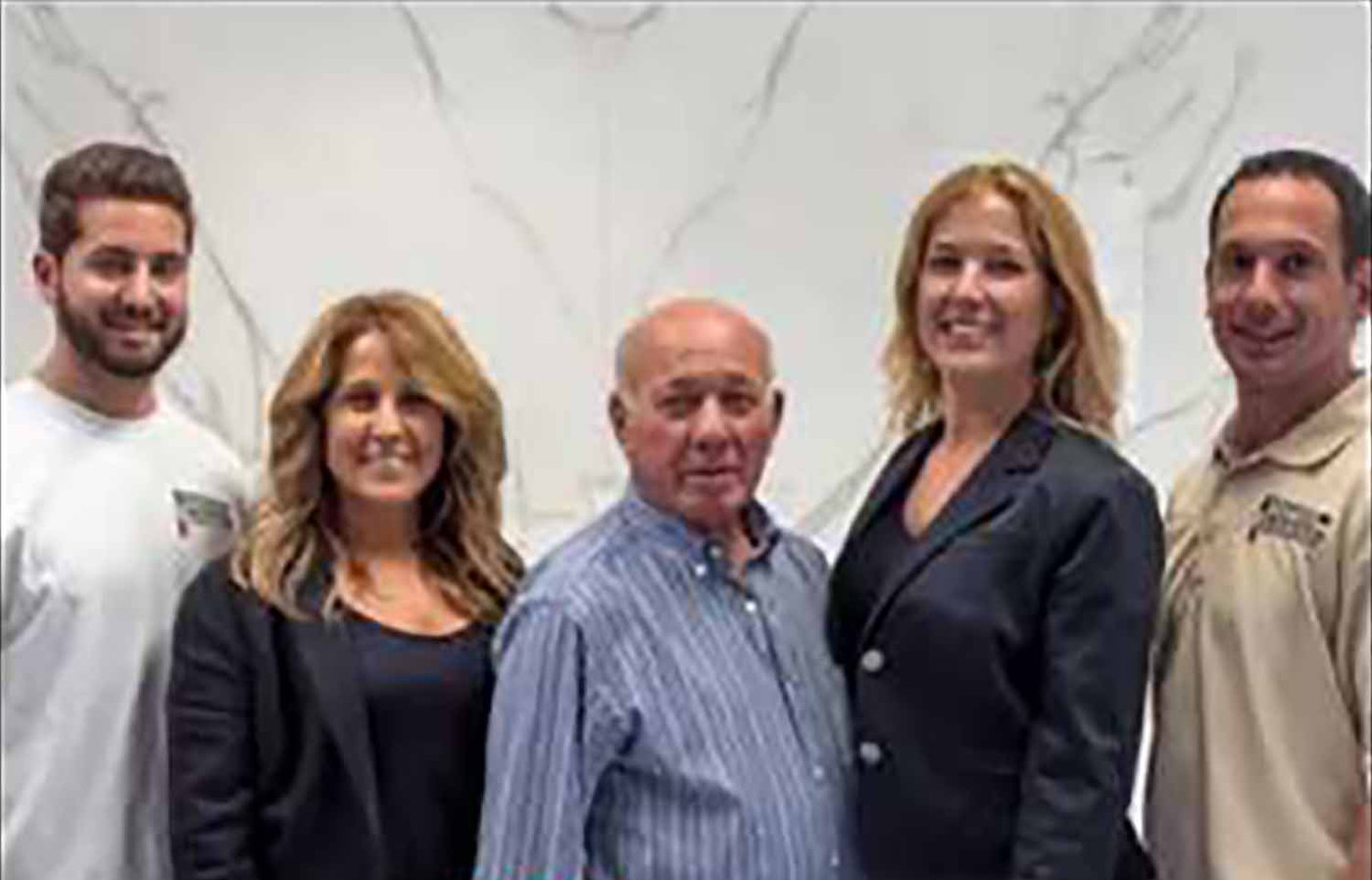 The Pistritto family team standing in front of a veined marble slab in their Hartford showroom