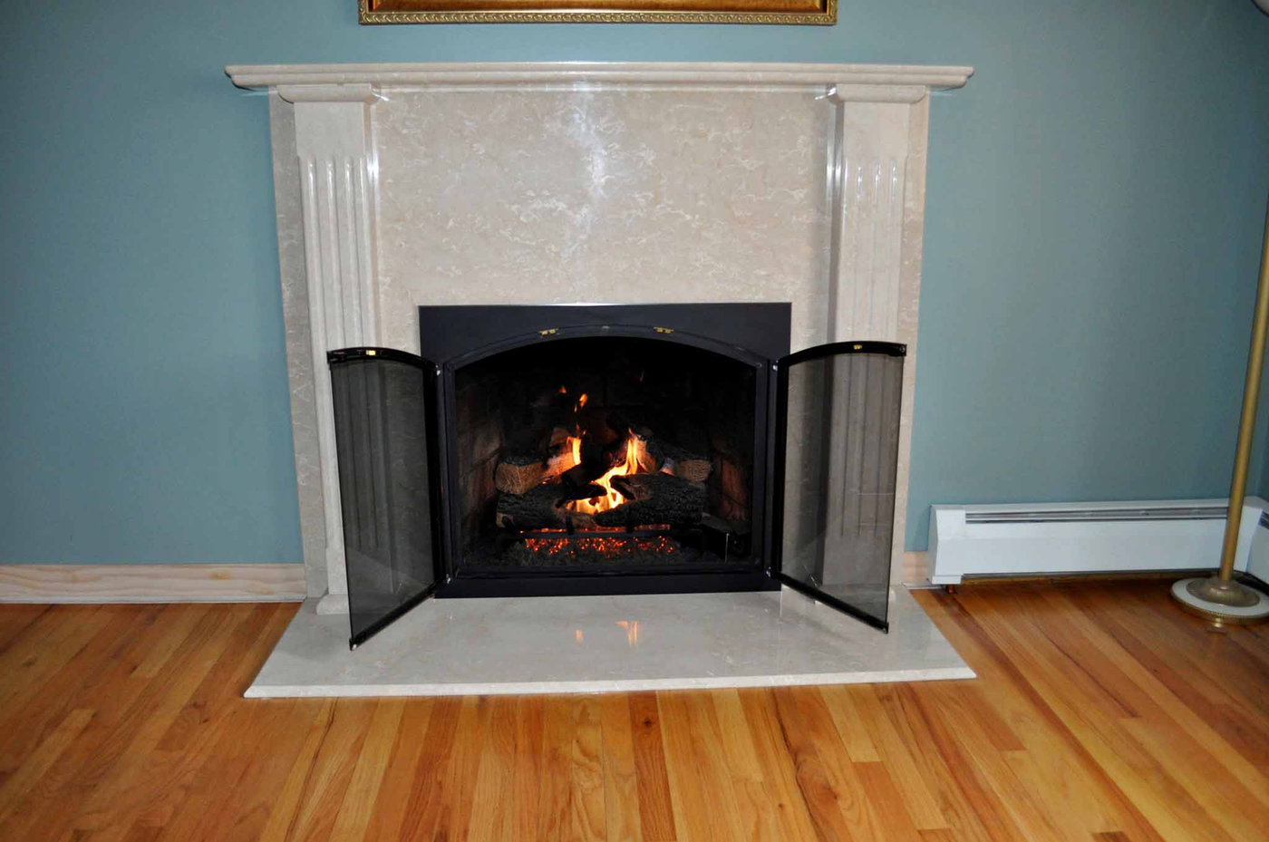 White marble fireplace surround with a lit fire