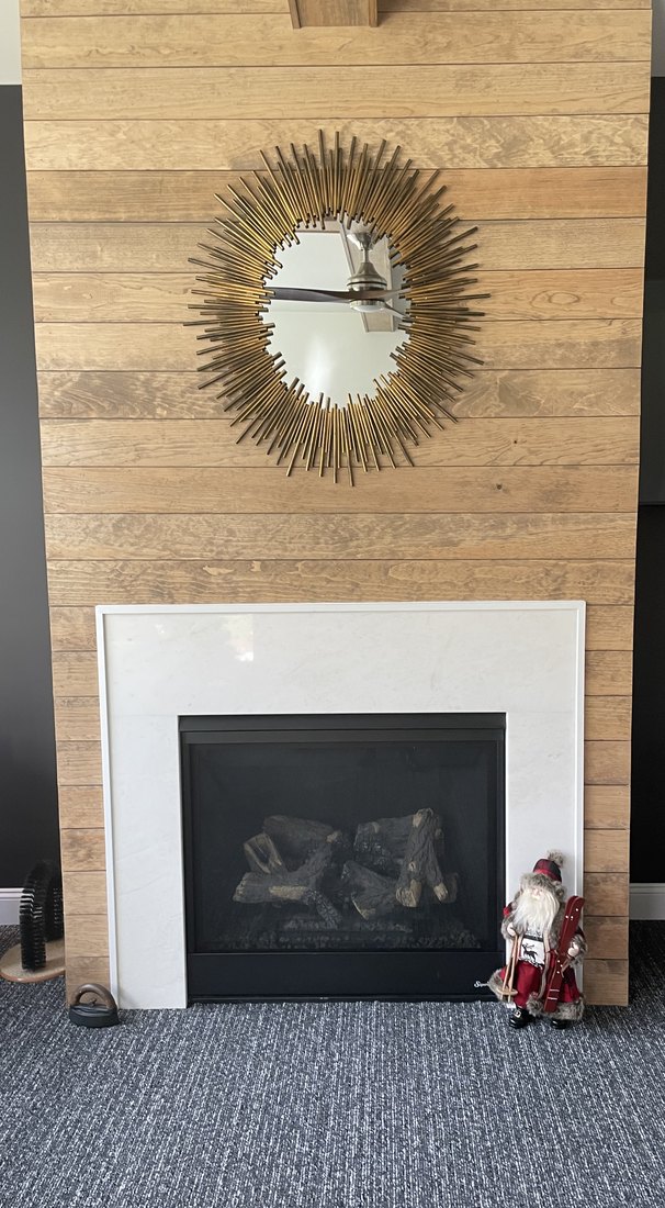 Fireplace surround by Pistritto Marble — pale stone surround and hearth against a wood plank wall
